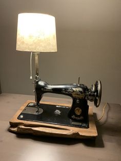 an old sewing machine sitting on top of a wooden table next to a white lamp