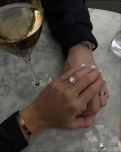 two people holding hands at a table with wine glasses