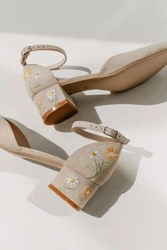 two pairs of women's shoes with flowers painted on the side, one in beige