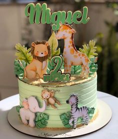 a two tiered cake decorated with animals and leaves