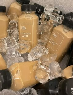 many different types of juices and bottles in ice cubes on a table top