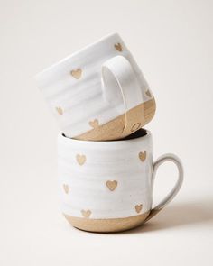 two white cups with gold hearts on them are stacked in the shape of heart mugs