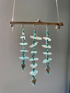 a wind chime hanging from a tree branch with sea glass beads and seashells