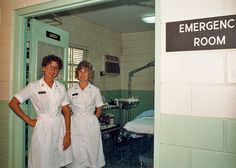 two women in white uniforms standing next to each other near a room with green walls