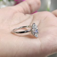 a person's hand holding a ring with a large diamond on the middle of it