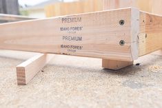 a wooden bench sitting on top of a cement floor next to a building with windows