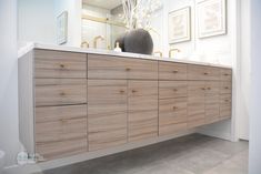 a bathroom vanity with wooden drawers and white counter top, in front of a mirror