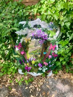 a mirror sitting in the middle of some plants and flowers on the ground with leaves around it