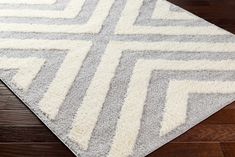 a gray and white rug on top of a wooden floor