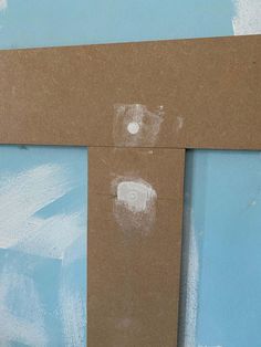 a piece of cardboard taped to the side of a wall with a cross painted on it