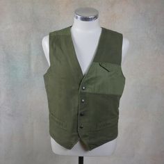 This olive army green cotton vest has a collarless V neckline and closes in the front with four snap buttons. The 1990s Italian vintage vest has three pockets on the front, and the back features a form-enhancing elasticated waistband. Condition: Excellent (Professionally Cleaned ... soft and supple, with no stains, tears, wear spots, or weaknesses in the seams)  Brand label: You & Me (Made in Italy)Size: Medium, 36/38 USMaterial: Cotton--- M E A S U R E M E N T S ---Chest = Up to 38 inches ( Vintage Cotton Vest With Button Closure, Cotton Vest With Snap Buttons For Work, Khaki Military Vest With Pockets, Khaki Utility Vest For Workwear, Fitted Green Vest With Button Closure, Green Buttoned Vest For Workwear, Sleeveless Military Outerwear, Retro Cotton Vest With Buttons, Spring Military Vest With Pockets