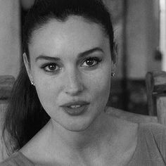 a black and white photo of a woman with her hair in a ponytail looking at the camera