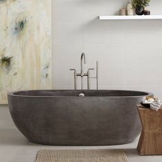 a bath tub sitting on top of a bathroom floor next to a wooden block and rug