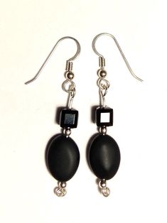 A pair of earrings with two jet black beads on sterling silver, the top bead being a faceted cube of Swarovski crystal and the bottom being an oval matte finished onyx bead.  Good for a goth or anyone else who appreciates lovely black jewelry. Onyx Bead, Black Jewelry, Black Beads, Onyx, Swarovski Crystals, Jewelry Earrings Dangle, Dangle Drop Earrings, Dangle Earrings, Jewelry Earrings