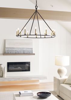 a chandelier hanging from the ceiling in a living room with white furniture and fireplace