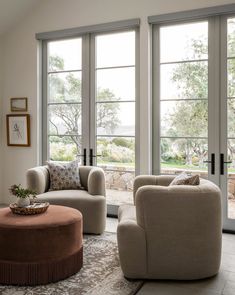 a living room with two couches and chairs in front of large windows that look out onto the outdoors