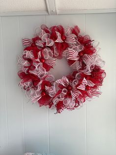 a red and white wreath hanging on the wall next to a basket with some candy in it