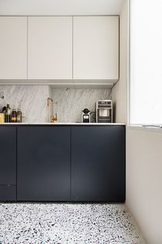 a kitchen with white cabinets and black counter tops, along with an area rug on the floor