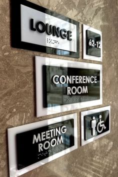 three signs on the wall that say conference room, meeting room and lounge