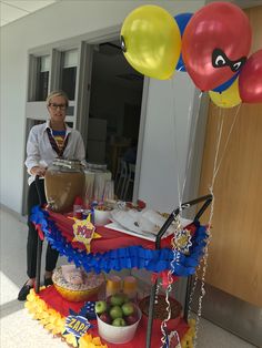 a woman standing in front of a table filled with food and balloons on top of it