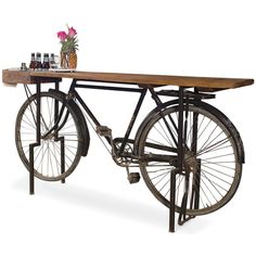 an old bicycle is sitting next to a table with bottles on it and flowers in vases