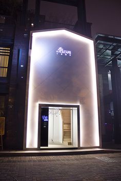 an entrance to a building lit up at night with lights on the outside and inside