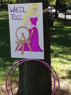 a sign that says wheel toss on it next to a tree with a drawing of a princess