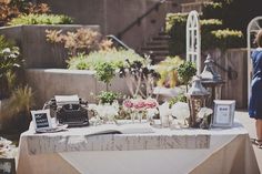 a table with flowers and an old typewriter is set up for a wedding reception