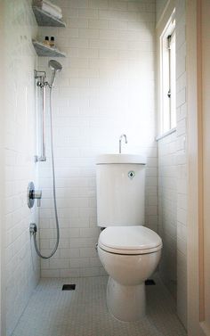 a white toilet sitting inside of a bathroom next to a shower head mounted on a wall