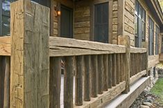 the front porch of a log cabin with wood railings and stone steps leading up to it