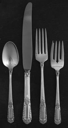 an assortment of silverware including forks, knives and spoons on a black surface