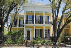 a large yellow house with blue shutters and balconies