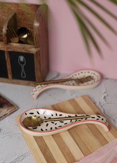 a wooden cutting board topped with two spoons