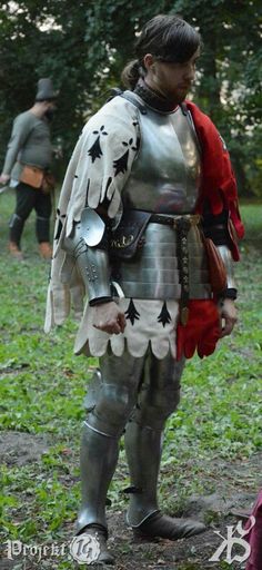 a man dressed as a knight standing in the grass