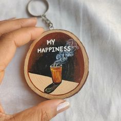 a hand holding a wooden keychain with an image of a cup on it