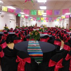 a banquet hall with tables and chairs covered in black tablecloths, red bows and sunflowers