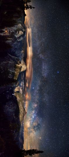 the night sky is filled with stars and clouds above a rocky cliff face, as seen from below