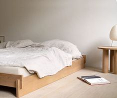 an unmade bed sitting on top of a wooden floor next to a night stand