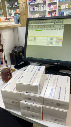 stacks of boxes sit in front of a computer screen on a desk at a pharmacy