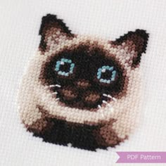 a cross stitch picture of a siamese cat with blue eyes and whiskers