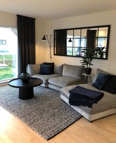 a living room filled with furniture next to a large window and a rug on top of a hard wood floor