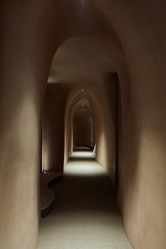 an empty tunnel with light coming in from the end and shadows on the wall behind it