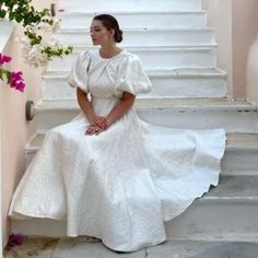 a woman in a white dress sitting on some stairs