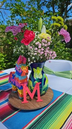 colorful flowers in a vase on a table with the letter m cut out from it