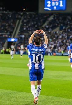 a soccer player is walking on the field with his arms in the air and one hand up above his head