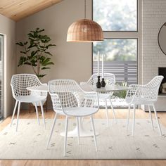 a white table and chairs in a room with a large window, potted plant on the far wall