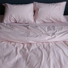 an unmade bed with pink sheets and pillows