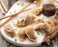 some dumplings are on a plate with chopsticks next to them and sauce