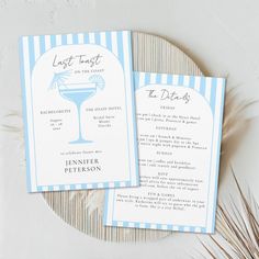 two blue and white striped menus on top of a table next to a plant