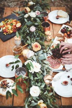 people sitting at a wooden table with plates and flowers on it, eating pizzas